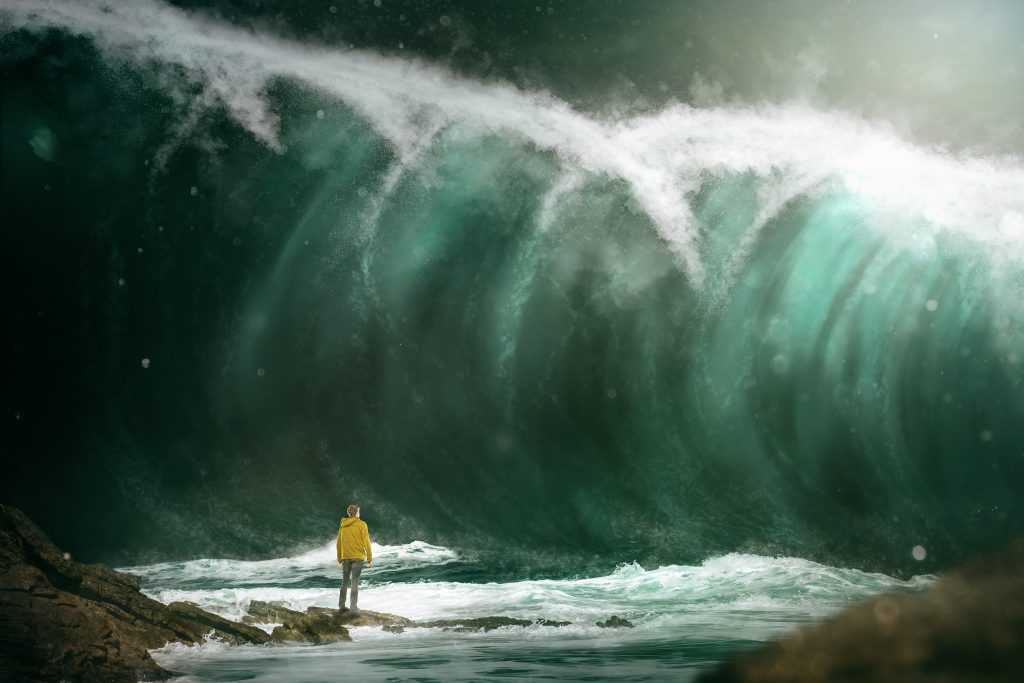 Photo of man in yellow rainjacket standing at base of tsunami