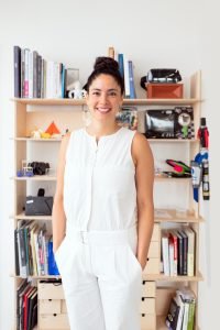 woman in white pant suit in front of bookshelves